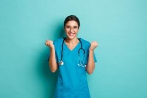 Smiling nurse holding her fists up against a solid backdrop